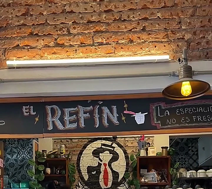 Barra de El Refin con su letrero y el mural del personaje de sombrero y corbata roja
