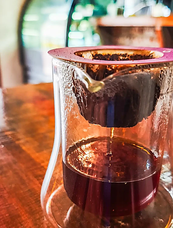 Bolsita de café de goteo sobre una taza de vidrio