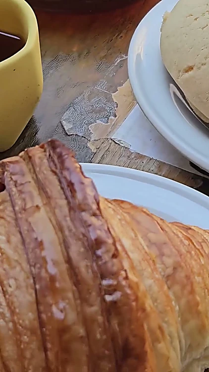 Croissant y concha en la mesa, junto a una taza amarilla