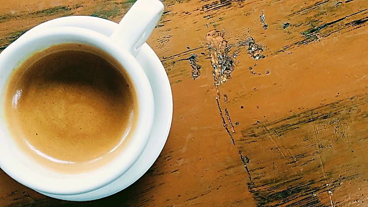 Espresso en taza blanca sobre una mesa de madera pintada